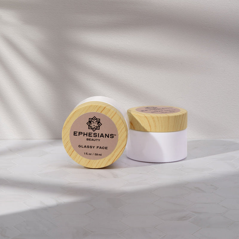 Two cosmetic jars with wooden lids on a light background